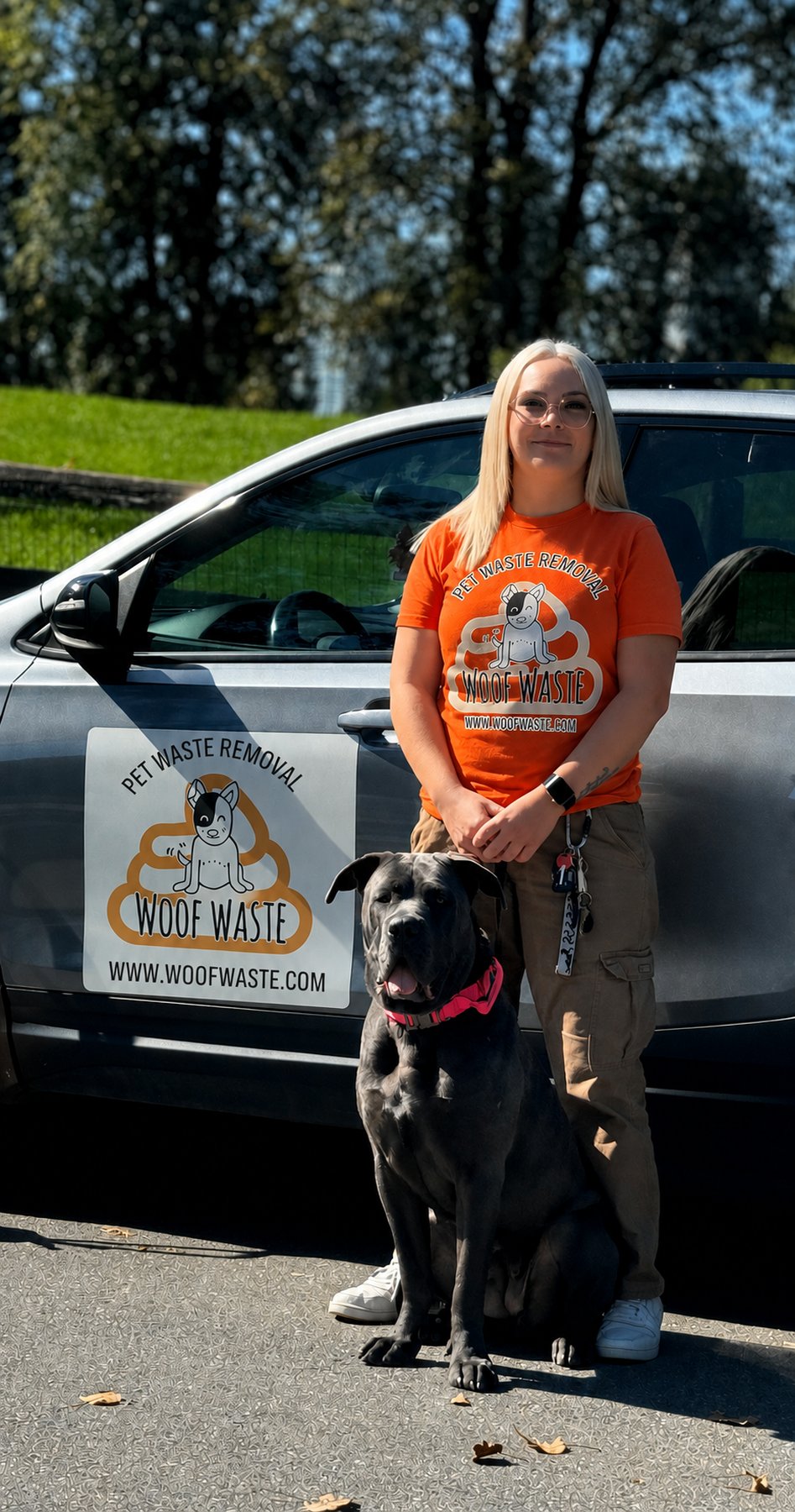 Kira from Woof Waste with a client's dog beside the branded Woof Waste vehicle